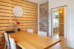 A wooden dining table with chairs, a clock, and a vase with flowers.