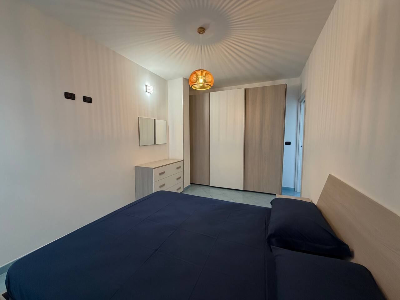 A bedroom with a bed, a dresser, a mirror, and a wardrobe.