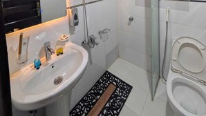 Et moderne badeværelse med vask, spejl, bruser og toilet.