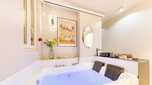 A modern bathroom with a bathtub, a mirror, a framed picture, and a vase with flowers.