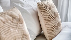 A close-up of a bed with white bedding and two pillows with a ribbed texture.