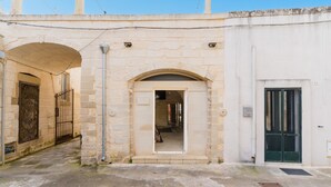 A stone building with an arched entrance, a metal gate, and a green door.