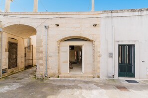 Un bâtiment en pierre doté d’une entrée en arc de cercle, d’un portail en métal et d’une porte verte.