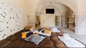 A stone-walled room with a bed, pillows, and towels.