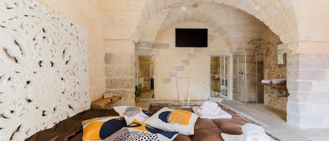 A stone-walled room with a bed, pillows, and towels.