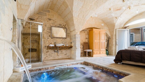 A stone-walled bathroom with a bathtub, a shower, and a sink.