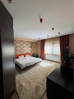 Ein Schlafzimmer mit einem Bett, einem Schreibtisch, einem Heizkörper und einem Fenster mit Vorhängen.