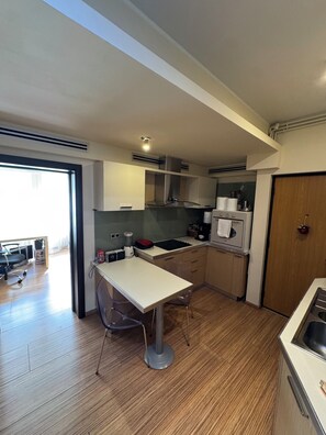 Eine kleine Küche mit Esstisch, Kaffeemaschine und Kühlschrank.
