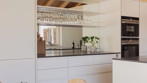 Una cuina moderna amb armaris blancs, un taulell negre i un forn de sobretaula.