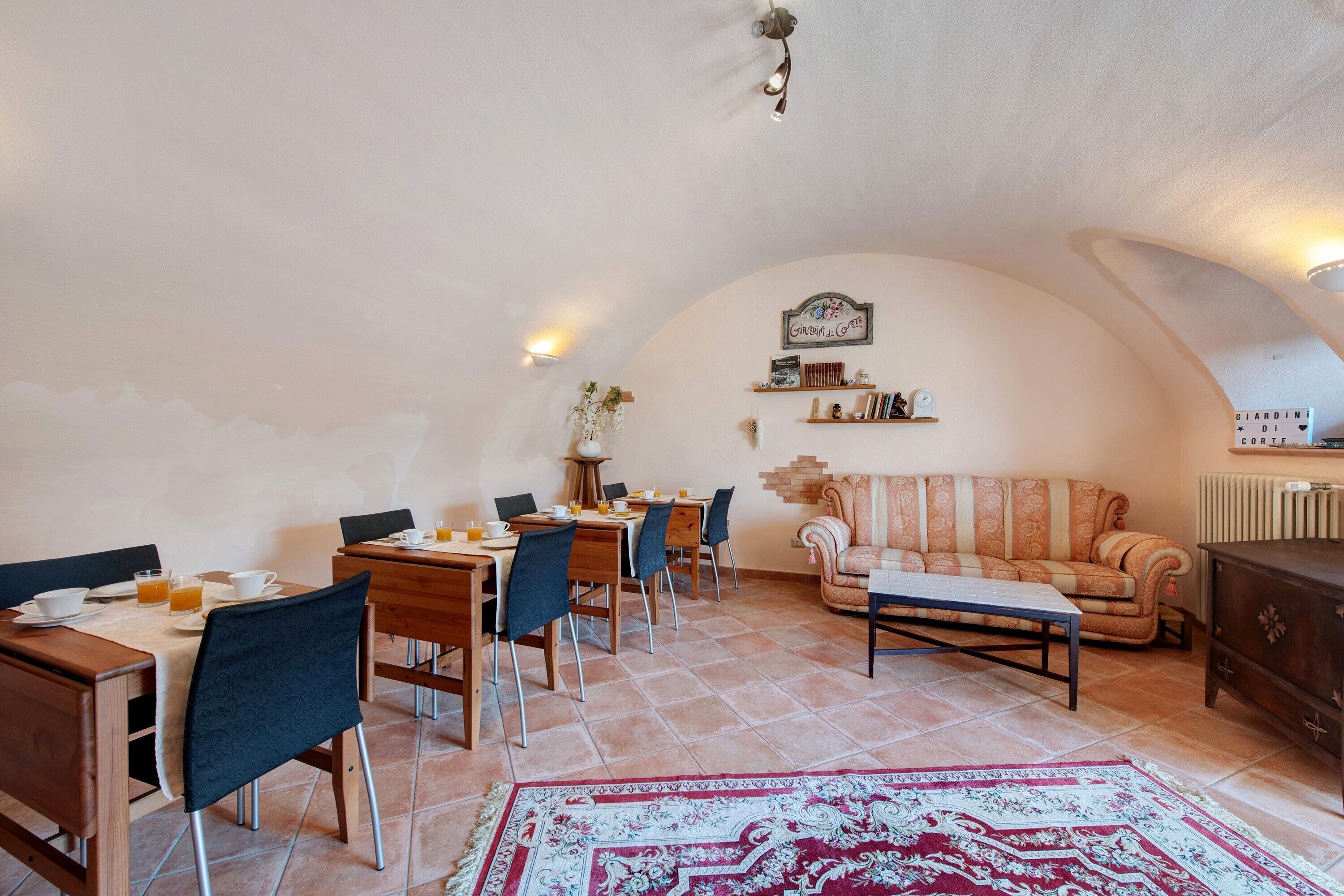 A dining area with tables and chairs, a sofa, and a decorative wall.