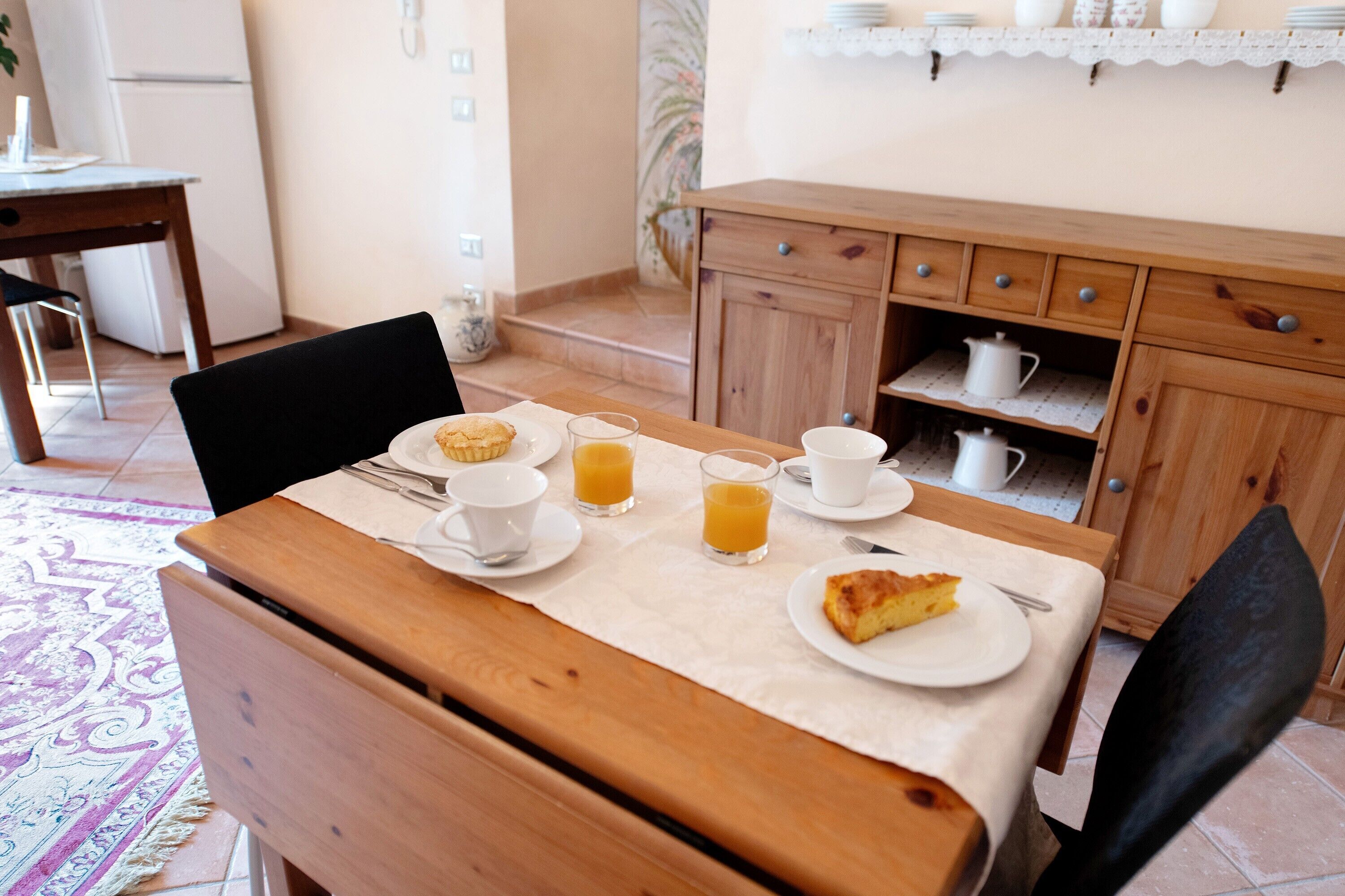 Un coin petit-déjeuner comprenant une table, des chaises, un buffet et un espace cuisine.