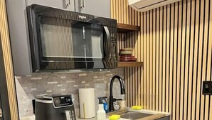 Una cocina compacta equipada con microondas, tostadora, lavaplatos y pileta.