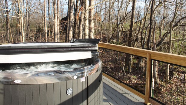 Un jacuzzi en una terraza de madera con vista a un bosque.