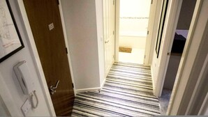 Un pasillo estrecho con un suelo a rayas que conduce a una puerta.