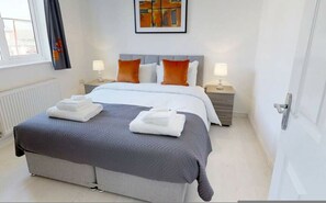 A hotel room with a bed, two bedside tables, a window, a radiator, and a painting on the wall. - Cole Green Lane Executive Stay- Free Parking (Welwyn Garden City)