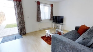A living room with a grey sofa, a TV, and a radiator. - Cole Green Lane Executive Stay- Free Parking (Welwyn Garden City)