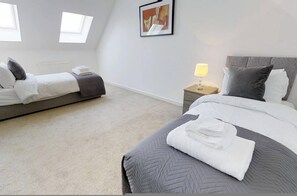 A hotel room with two beds, a radiator, a lamp, and a painting on the wall. - Cole Green Lane Executive Stay- Free Parking (Welwyn Garden City)