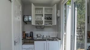 A compact kitchen with a washing machine, a sink, and a cabinet above the counter. - Modern London Studio 15mins to Central London (London)