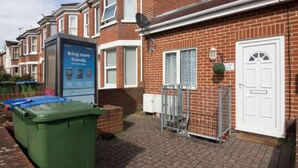 A residential area with houses, a green bin, and a metal gate. - Southampton 2-bedroom House (Southampton)