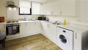A compact kitchen with a built-in washing machine, a microwave, and a toaster. - Castle Point 6 Apartment - Premier Lodge (Southampton)