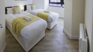 A hotel room with two beds, a window, a radiator, and a painting on the wall. - Castle Point 6 Apartment - Premier Lodge (Southampton)