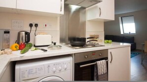 Eine kompakte Küche mit Geschirrspüler, Backofen und Toaster. Ein Fenster sorgt für natürliches Licht und Blick ins Freie.