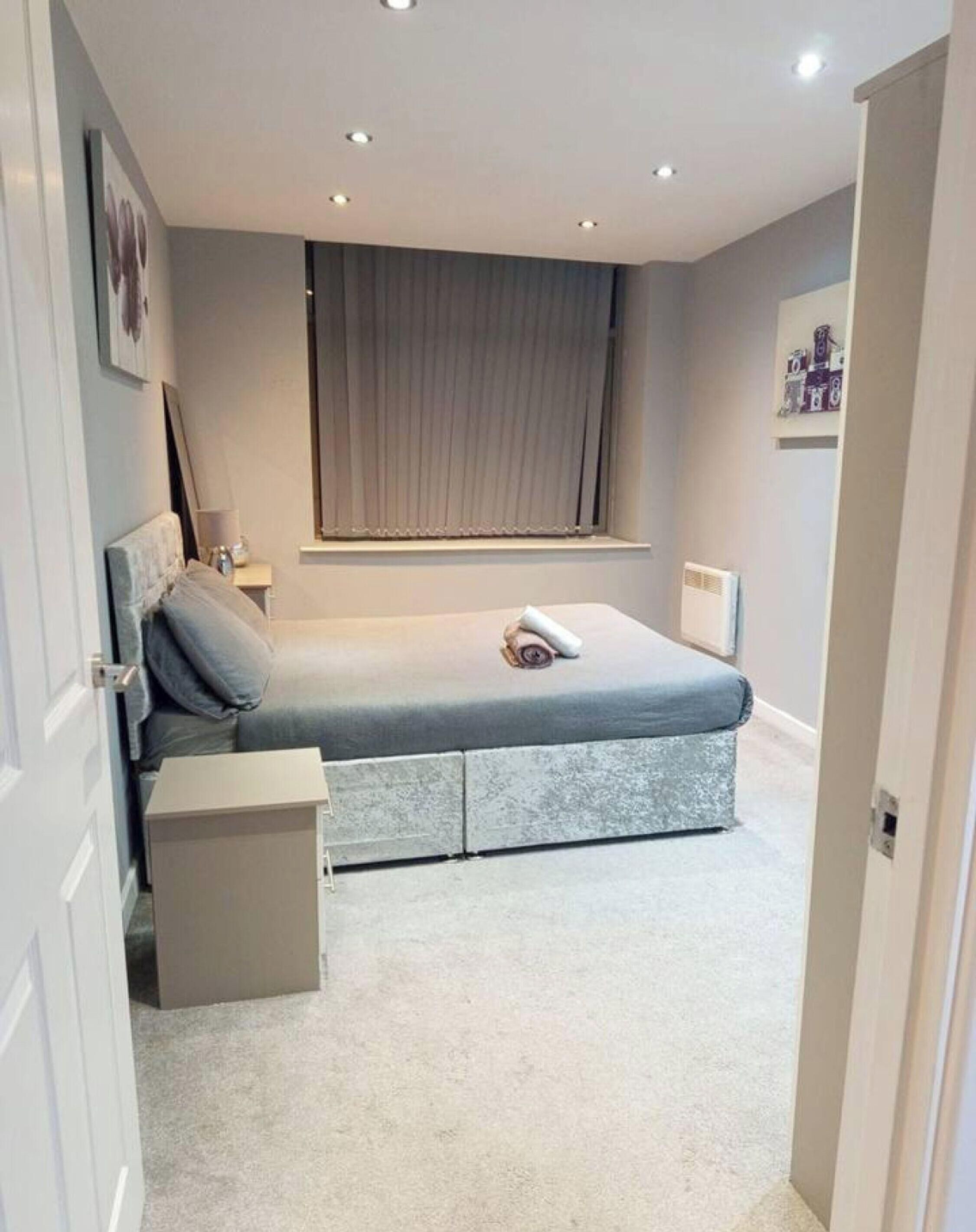 A bedroom with a bed, bedside tables, a window with curtains, and a door.