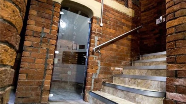 A staircase with metal handrails and brick walls, leading to a door with a frosted glass panel. - Bradford City Victorian Mill Escape Apartment 3 (Bradford)