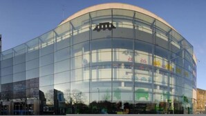 A modern glass building with a curved facade and a visible logo on the upper part. - Bradford City Victorian Mill Escape Apartment 3 (Bradford)