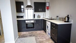 A compact kitchen with a microwave, oven, and washing machine. - Bradford City Victorian Mill Escape Apartment 3 (Bradford)