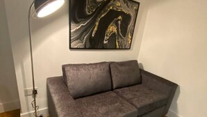 A modern living room with a grey sofa, a black floor lamp, and a marble artwork on the wall. - Stylish 2BR Serviced Apartment in Bedford Centre 4 (Bedford)