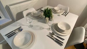 A dining table set with plates, cutlery, and glasses, a small plant, and a mirror on the wall. - Stylish 2BR Serviced Apartment in Bedford Centre 4 (Bedford)