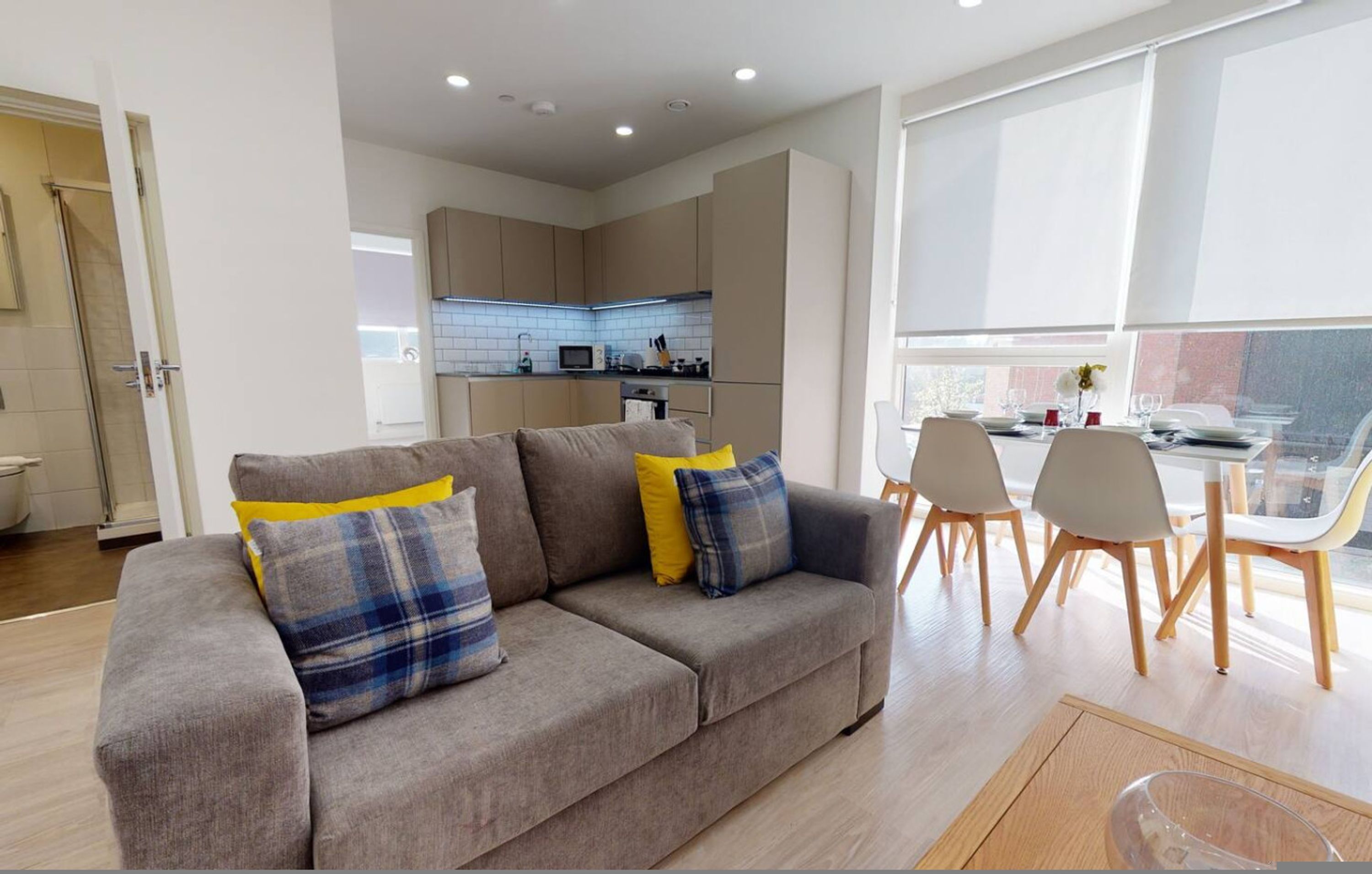 A modern living room with a sofa, dining table, and chairs.