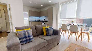A modern living room with a sofa, dining table, and chairs.