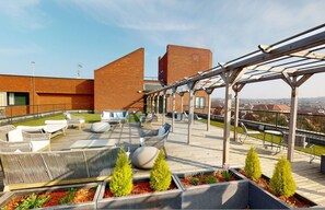 Una terrazza sul tetto con posti a sedere all'aperto, un pergolato e vista sulla città.