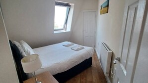 A bedroom with a bed, a window, a radiator, and a door. - Comfortable Southampton Stay (Southampton)