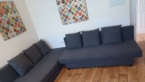 A modern living room with a dark grey sectional sofa, a smaller sofa, and a wooden floor. - Comfortable Southampton Stay (Southampton)
