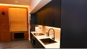 A modern kitchen with dark cabinets, a white countertop, and a built-in sink. - Nichols Building City Escape Spacious 3BR Sheffield (Sheffield)