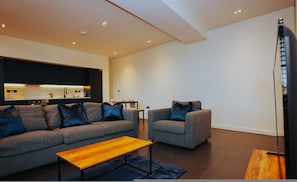 Ein modernes Wohnzimmer mit Sofa, Sessel und Couchtisch.