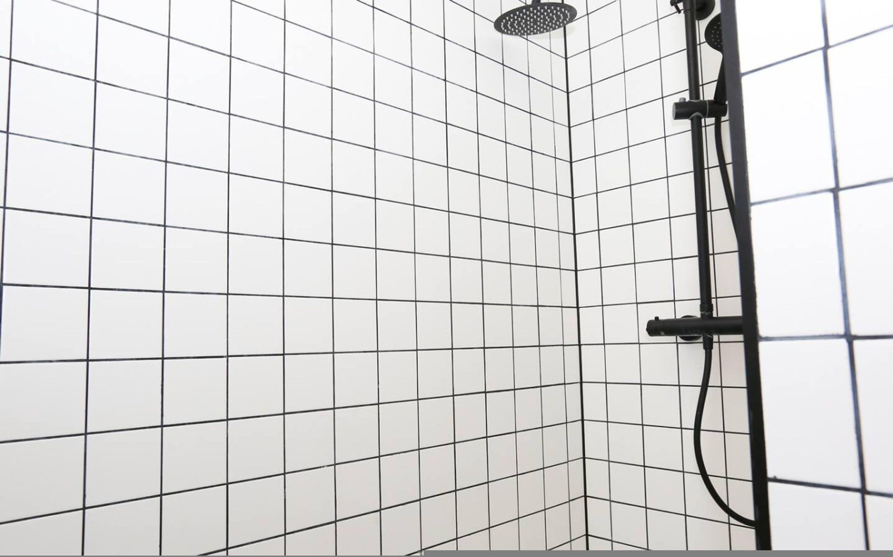 A tiled shower area with a handheld showerhead and a wall-mounted faucet.