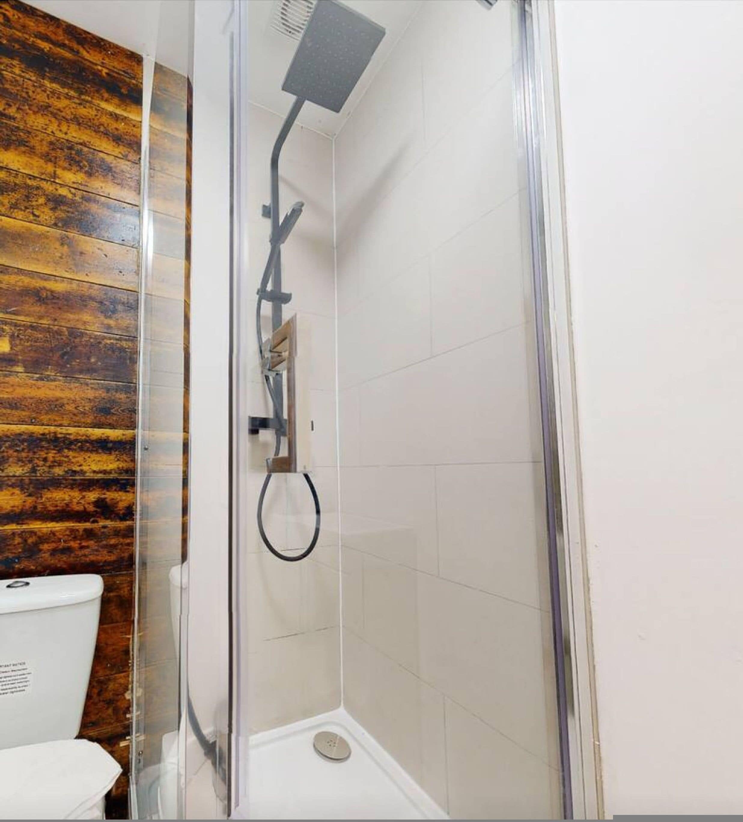 A shower enclosure with a glass door, a showerhead, and a tiled floor.
