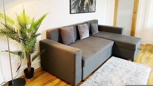A modern living room with a grey sofa, a floor lamp, a large abstract painting, and a potted plant. - Stylish Bedford Town Centre Apartment 5 Sleeps 6 Fast Wi-fi (Bedford)