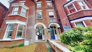 A brick building with a central entrance, a blue door, and a sign indicating it is a guest house. - De Pary 2 Modern Bedford Apartment- Near Town Centre (Bedford)