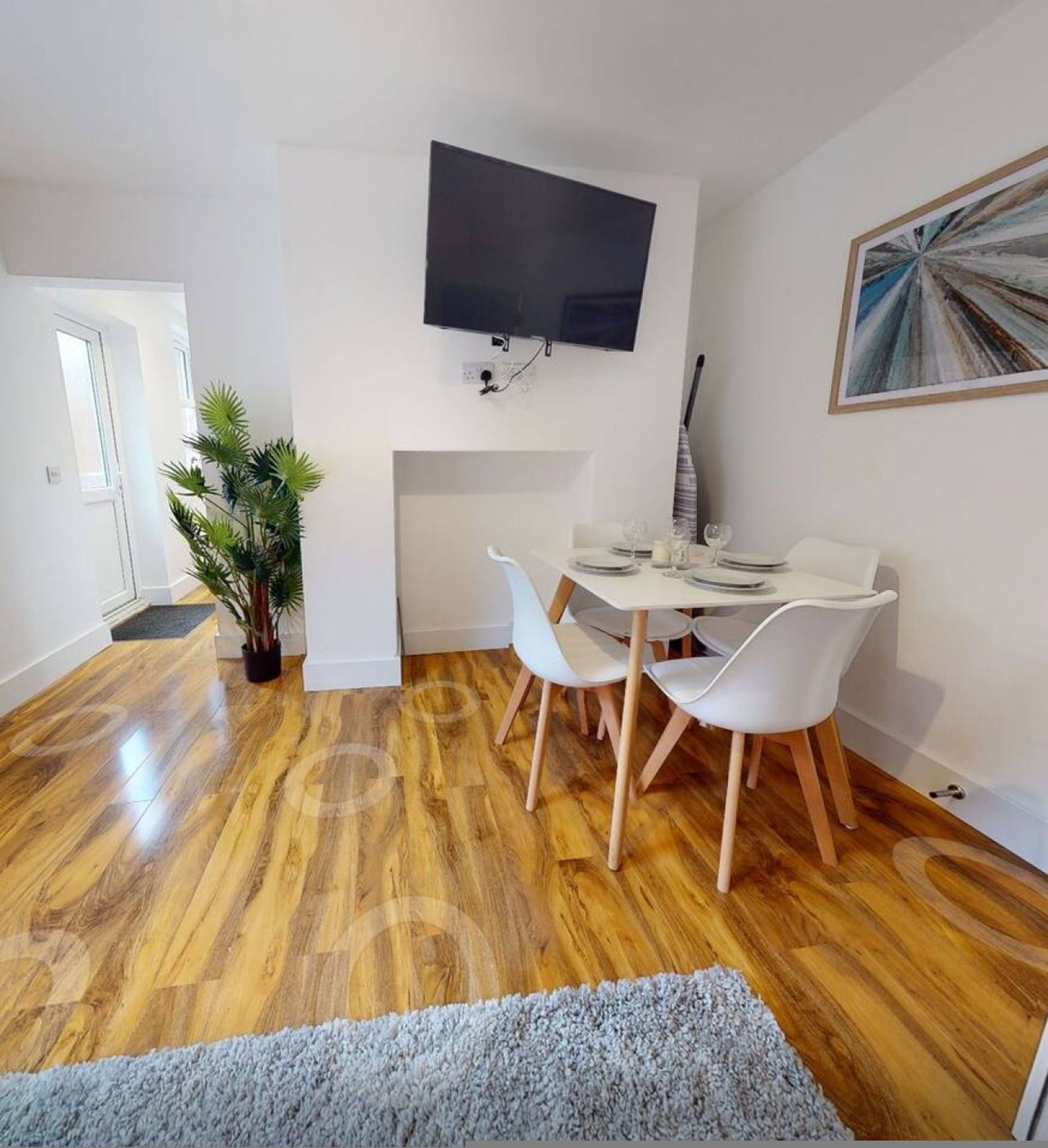 A dining area with a table, chairs, a flat-screen TV, and a fireplace.