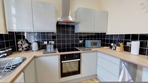 A compact kitchen with white cabinets, a microwave, a kettle, and a sink. - Westminster Luxe Stay City View 3BR Bradford (Bradford)