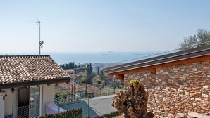 Zona residencial con tejado de baldosas, pared de piedra y vista al mar.