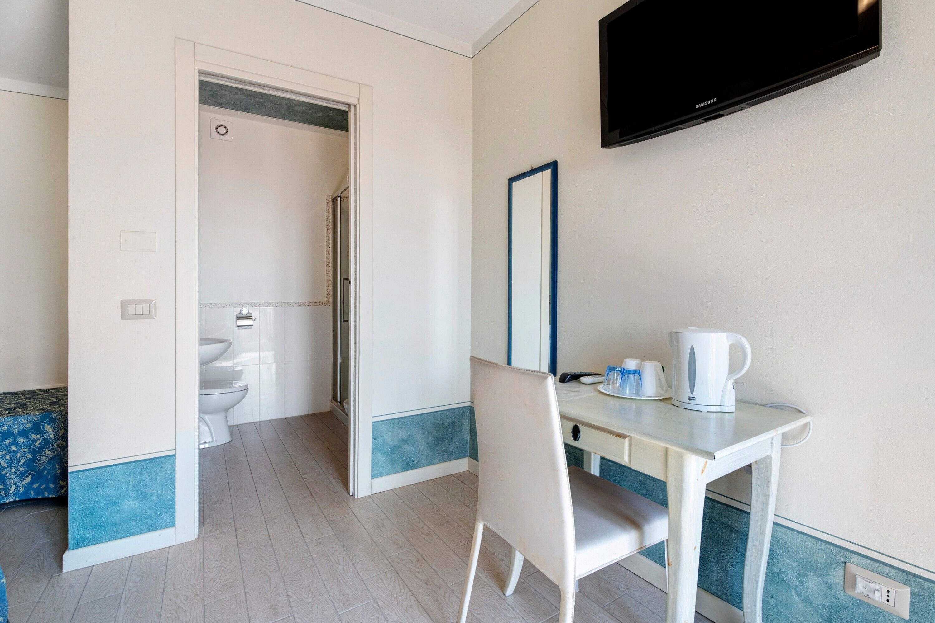 Ein Hotelzimmer mit Schreibtisch, Stuhl und einem an der Wand befestigten Fernseher.