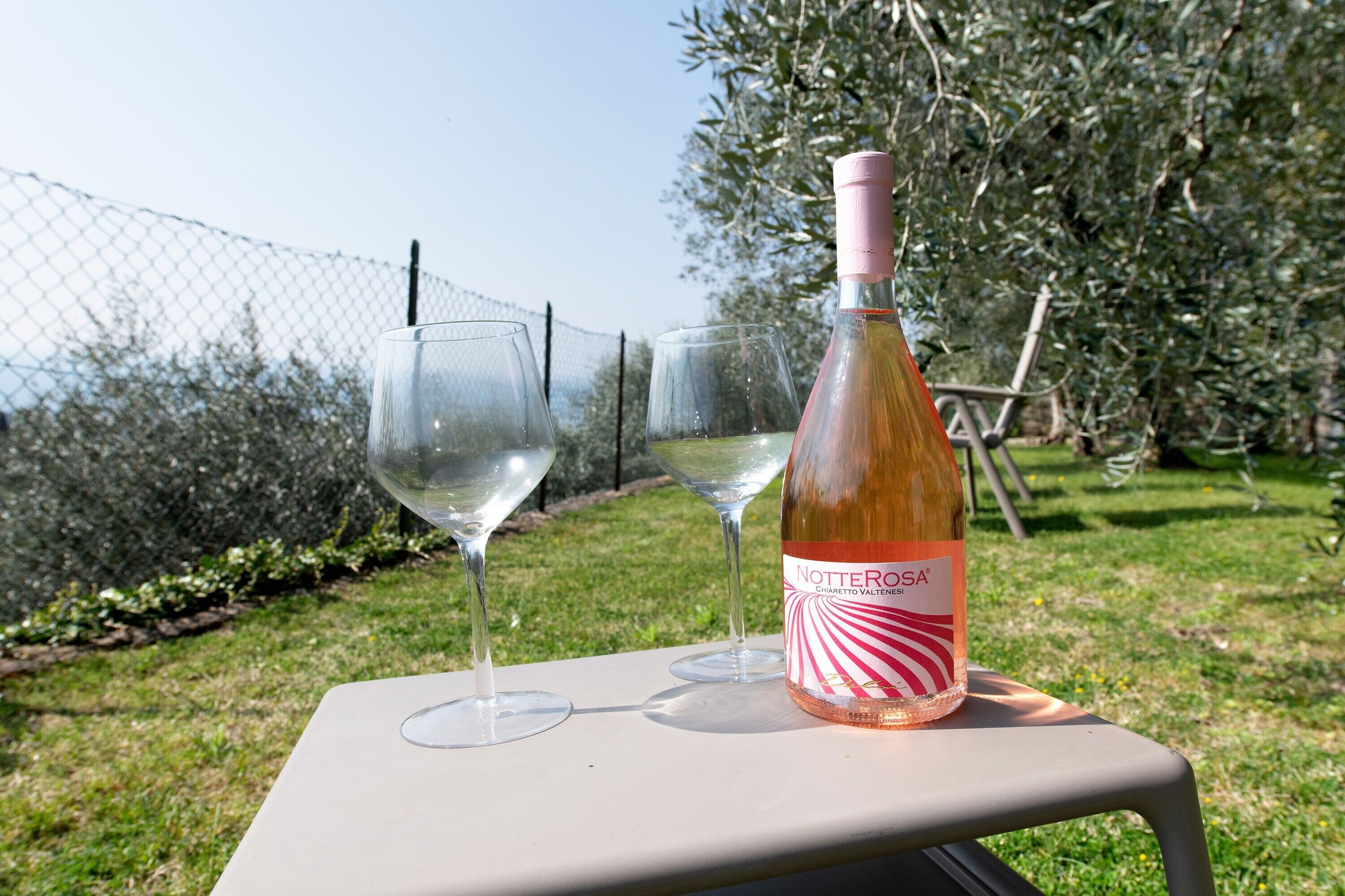 Eine Flasche Notte Rosa Wein auf einem Tisch mit zwei leeren Weingläsern.