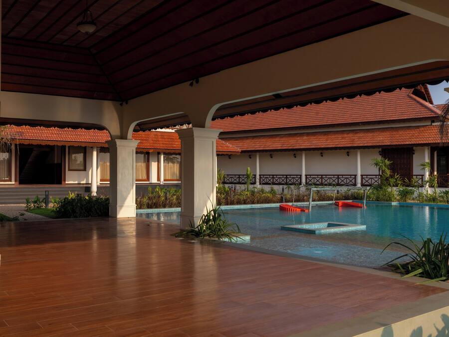 A covered pool area with a wooden floor, tiled roof, and a clear view of the pool.