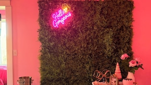 A room with a neon sign, a wall-mounted plant, a table with decorative items, and a checkered floor. - Beautiful Creekside loft over Historic Mannington  (Mannington)